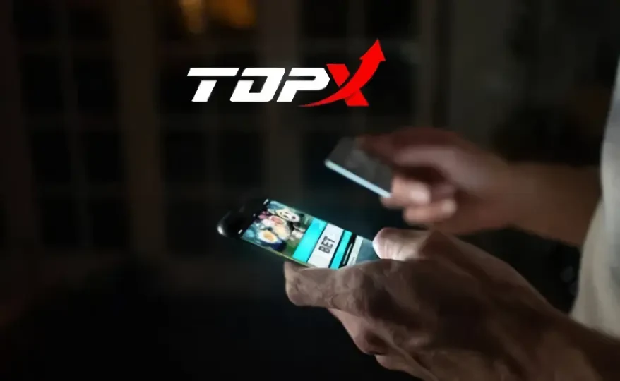 Imagem de marca da TopX: mãos usando um celular num ambiente escuro